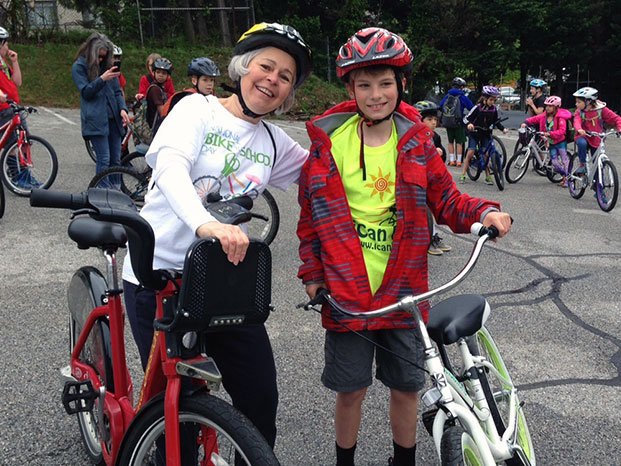 Photo of Lucy Neher and iCan Shine Bike Camp graduate Lev pose with their bikes on Bike to School Day 2016 in Takoma Park